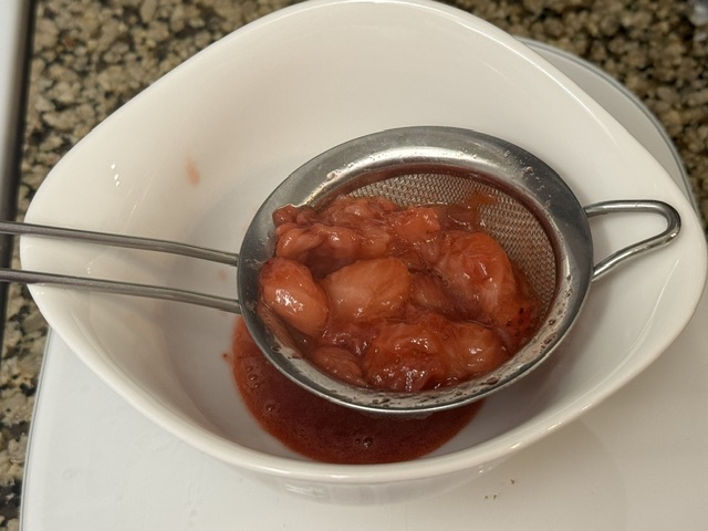 Solides de fraise dans un tamis sur un bol