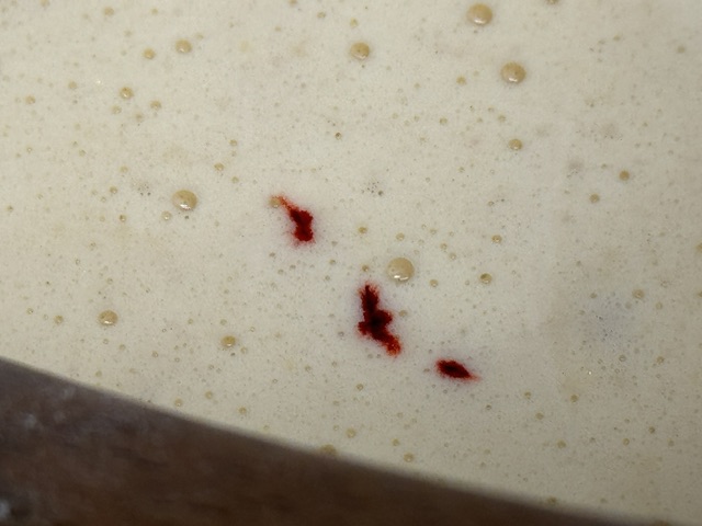 Gouttes de colorant rouge flottant sur la surface en gros-plan