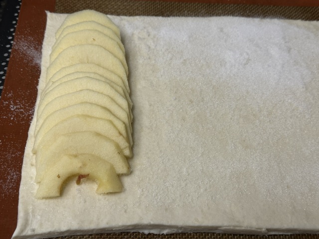 Un rang de tranches de pommes posé sur la pâte