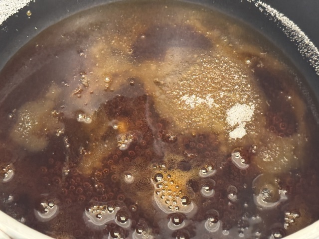 Caramel presque prêt -- il y a du liquide marron partout, des bulles visibles ici et là, et juste un petit peu de sucre
