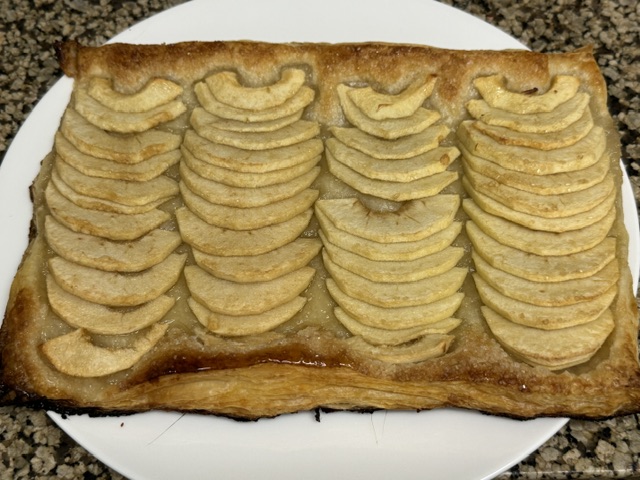 Tarte aux pommes sur l'assiette, mais sans l'avoir badigeonnée de caramel -- la pâte est bien gonflée, les pommes sont bruns et un peu sechées, et on peut voir de la cassonade toujours sur les pommes.
