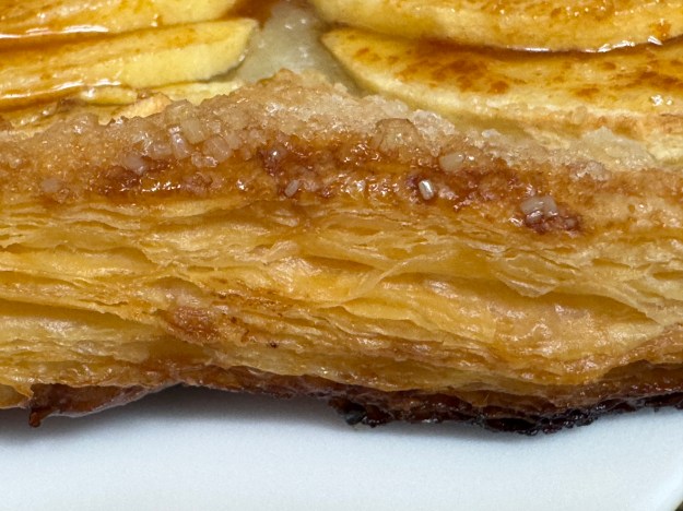 Une autre vue du feuilletage qui permet de voir des pommes avec, ainsi qu du sucre autour des pommes ; le jus des pommes a empêché une caramélisation complète, mais c'est toujours cuit.