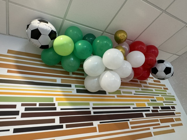 Des ballons verts, blancs et rouges, entourés de deux ballons en forme de ballon de foot.