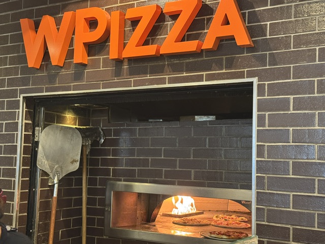 Four de bois sous un panneau en orange, W Pizza.
