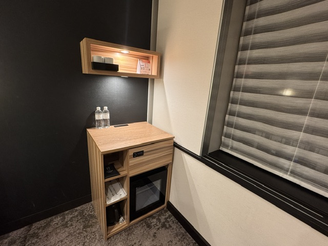 Chevet avec un petit frigo et des prises pour charger un portable