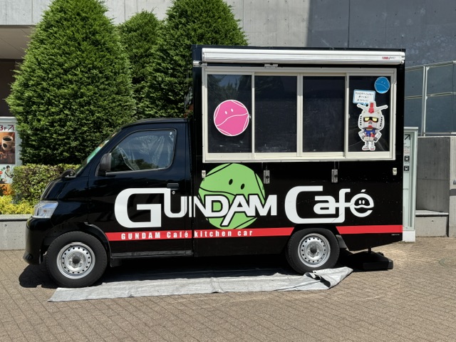 Vue de côté -- camion noir avec "Gundam Café" en lettres blanches