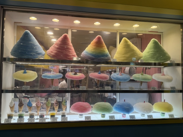 Vitrine avec les nombreuses barbes à papa, en cône géante ainsi que disque autour d'un cornet de glace