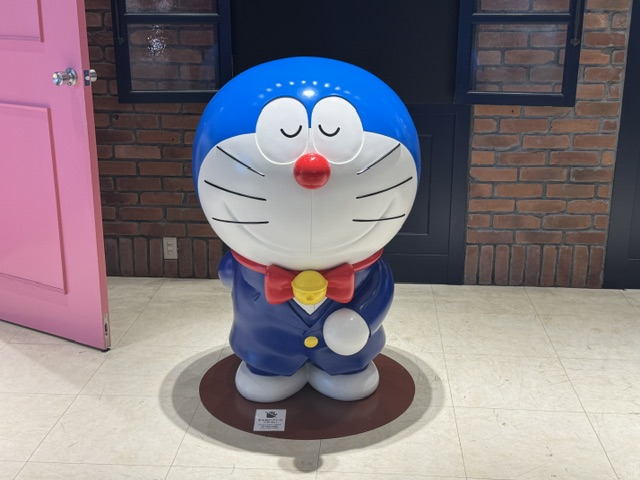Statue de Doraemon, qui a des poils bleus et un visage blanc. Il porte un smoking bleu.