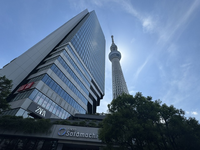 Du sol, on peut voir la pancarte du Tokyo Solamachi à environ 20 mètres. À gauche, il y a un gratte-ciel de 17 étages, et au centre, la tour, beaucoup plus mince mais avec 634 mètres de haut.