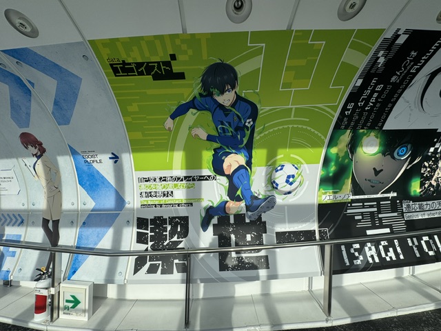 Passerelle décorée avec des dessins de la série Blue Lock. Un gars donne un coup de pied à un ballon.