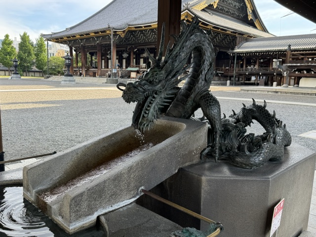 Vue de côté de la fontaine. Le dragon verse de l'eau dans un récipient rectangulaire en pierre