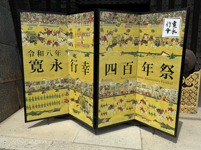 Écran jaune décoré avec des dessins des paysans, et un message sur les 400 ans de la visite impériale. 