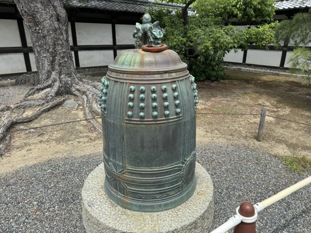 Cloche en métal vert -- probablement du cuivre. C'est en forme cylindrique, avec des inscriptions en japonais sur les côtés 