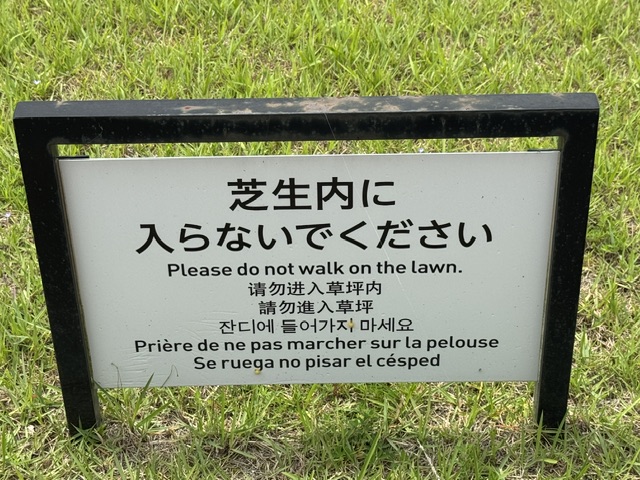 Panneau avec un message pour interdire marcher sur la pelouse, traduire en 7 langues 