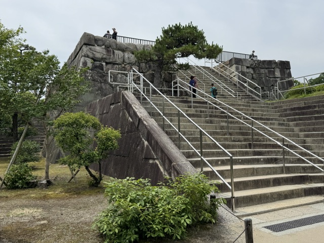 Escalier qui mène jusqu'à une tour rectangulaire en pierre. Seulement une partie plate attend le visiteur