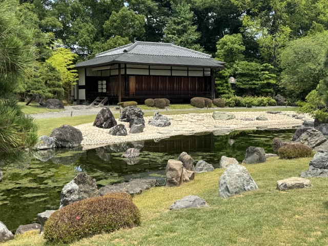 Café Sabo Maeda, un bâtiment en bois d'un étage. Il y a un ruisseau devant. 