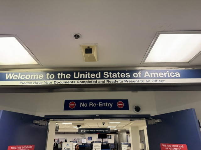 C'est l'entrée au hall où les passeports sont contrôlés à Los Angeles -- le panneau sur la porte dit « Bienvenue aux États-Unis d'Amérique ».