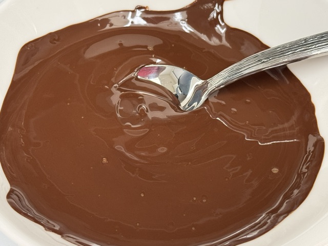 Bol de chocolat fondu avec une cuillère en métal posée au centre du bol