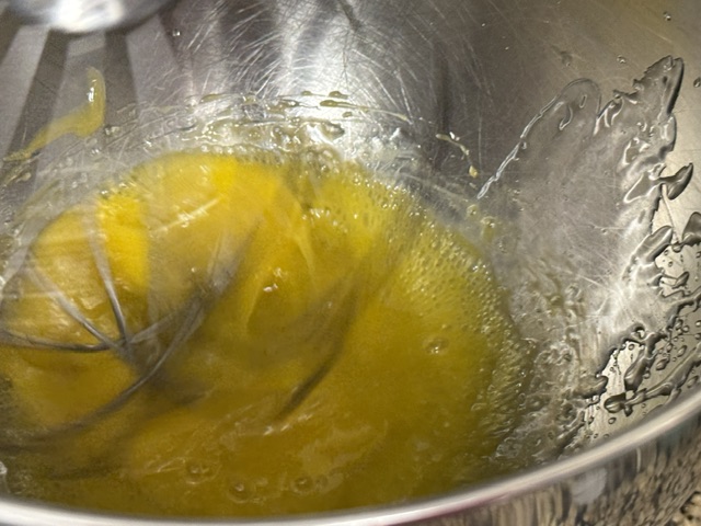 Jaunes fouettés alors que le sirop est versé au-dessus -- photo prise avec une main en versant le sirop avec l'autre