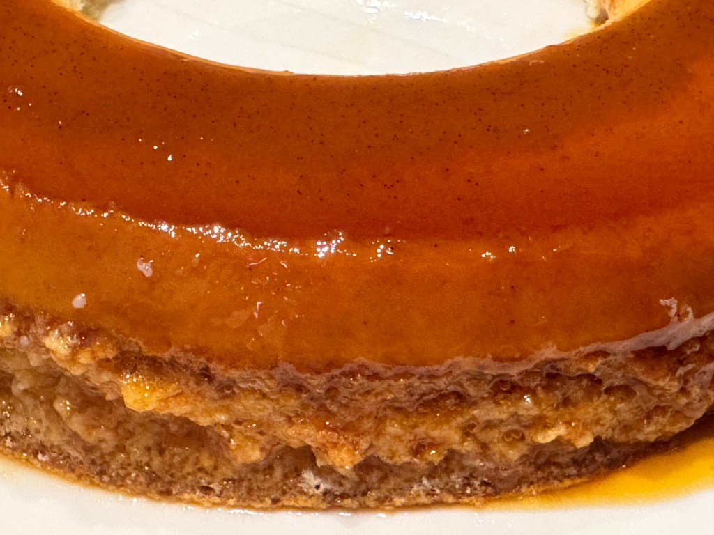 Gros-plan du bord ; on peut voir un haut très lisse, recouvert de caramel, puis une ligne où le caramel arrête soudainement et laisse place au gâteau.