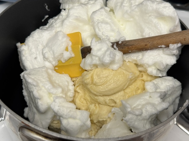 Blancs en neige versés sur la pâte. Une maryse avec une tête jaune est posée au centre