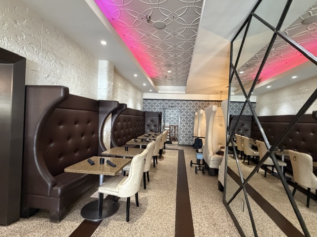 C'est très chic -- des banquettes en cuir noir, le mur à droit couvert en miroirs, un néon rose qui étend de l'un bout de la pièce à l'autre sur le plafond.