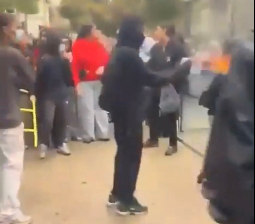 C'est un homme cagoulé, tout en noir, qui utilise un spray comme lance-flammes maison. La photo est taillée pour ne pas montrer la victime.