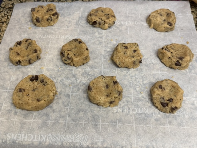 Dix cookies prêts à enfourner sur du papier de cuisson