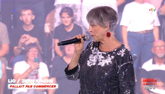 Lio en gros plan avec un micro. Elle a des cheveux pleinement gris