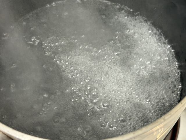Eau bouillante avec le bicarbonate -- c'est presque blanc dans l'eau, qui a presque atteint les bords de la casserole